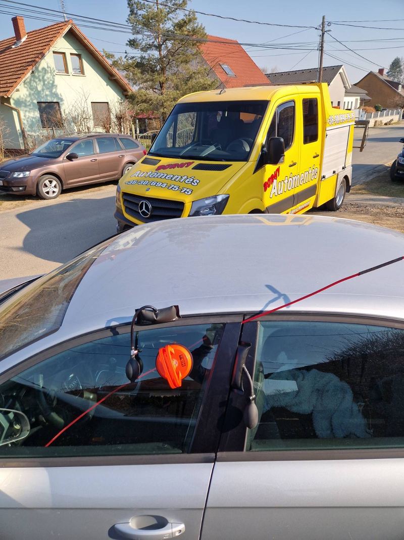 Autóajtó nyitása bezárt kulcs esetén, háttérben az emelővontató